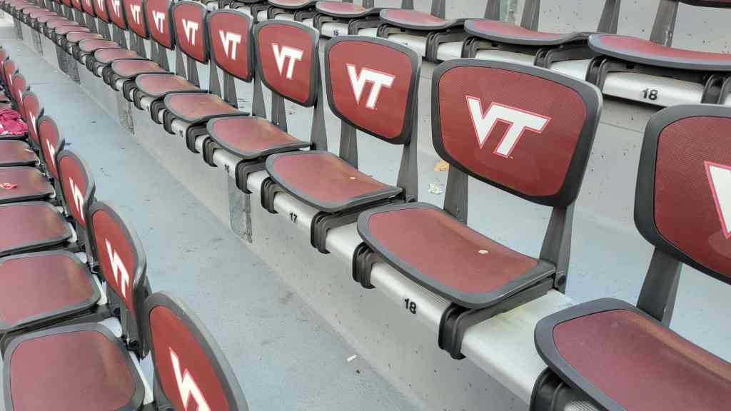 Empty stadium seats featuring the Virginia Tech logo, arranged in rows.